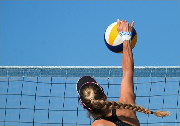 a woman is reaching up to hit a volleyball