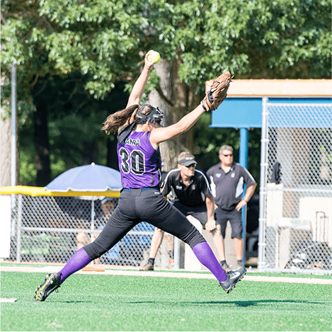 a softball player in the air catching a ball