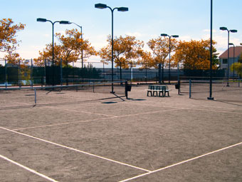 an empty tennis court with several lights on each side