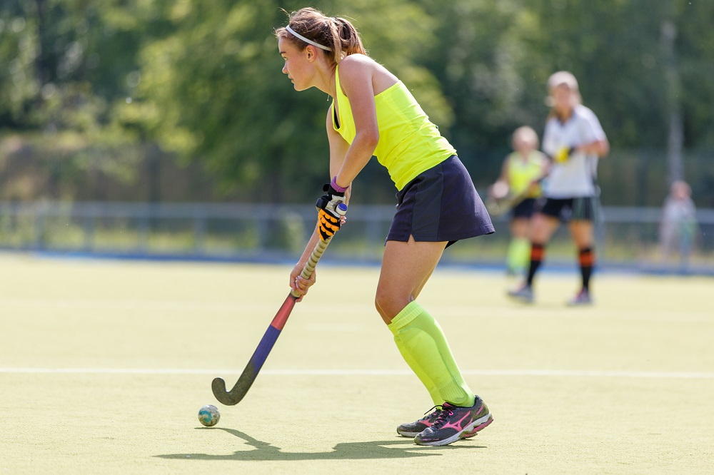a woman playing field hockey on a sunny day