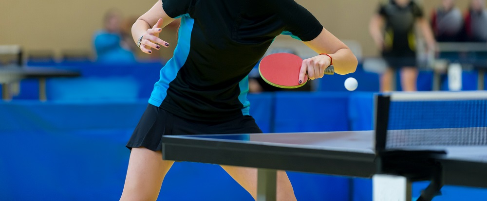 a woman is playing ping pong in a gym